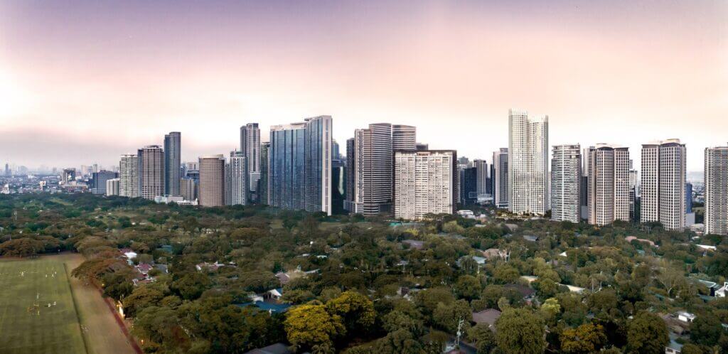 Dusk aerial shot of city skyline with modern high-rise buildings and dense green parkland in foreground.
