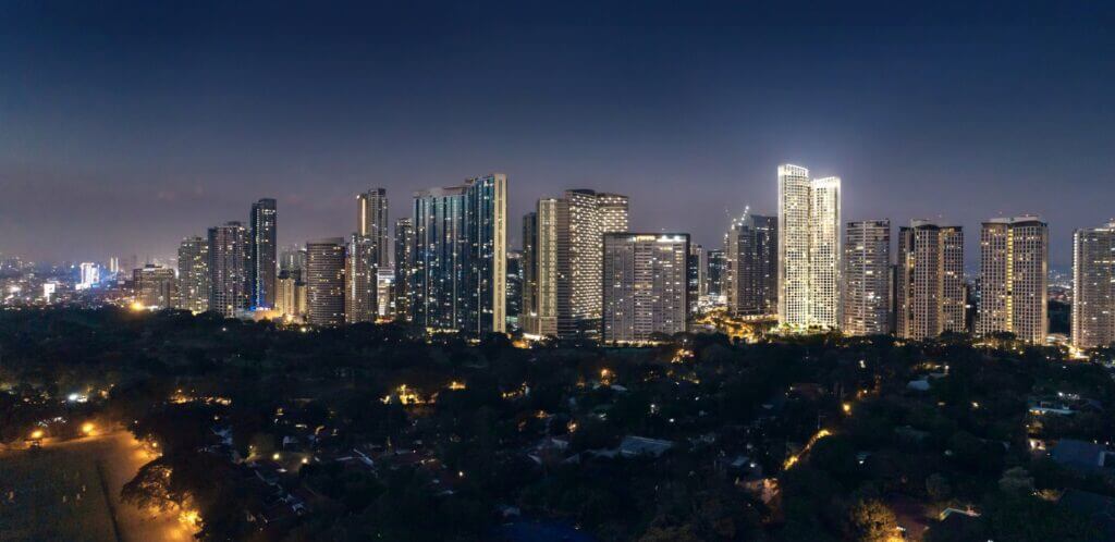 Nighttime aerial view of illuminated city skyscrapers under dark sky.