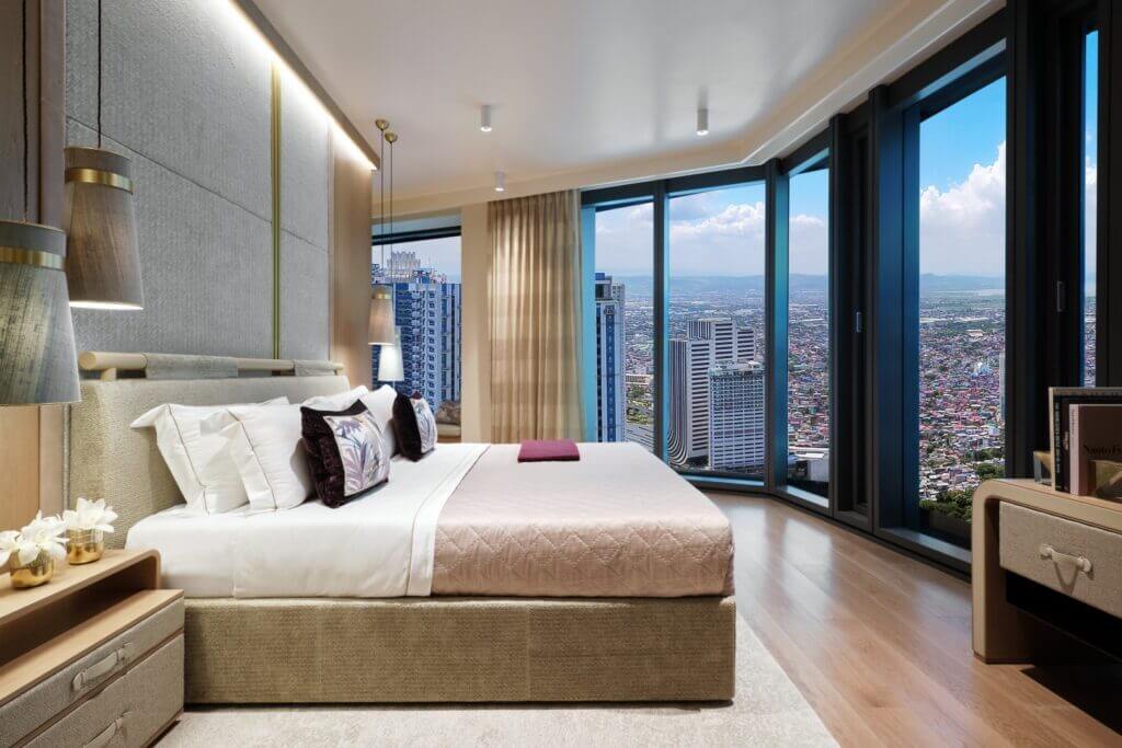 Interior rendering of a master bedroom with floor-to-ceiling windows overlooking a city, featuring a large bed with neutral-toned linens.