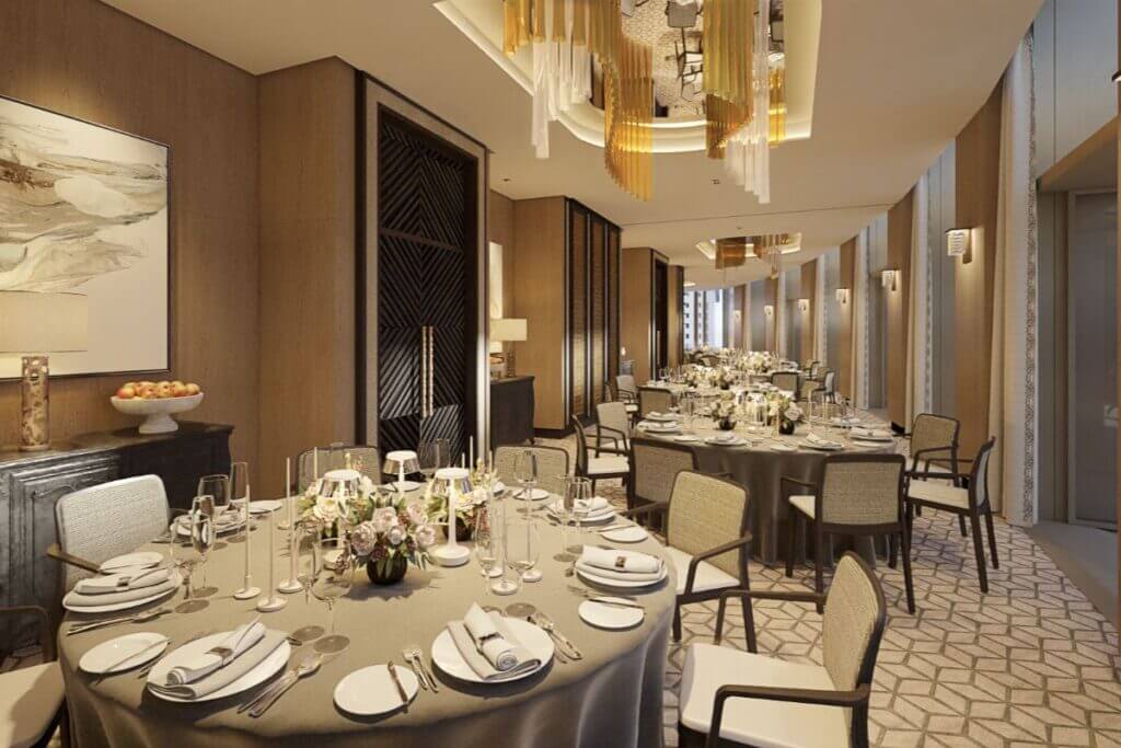 Sophisticated banquet hall featuring round tables with formal place settings and white floral centerpieces.