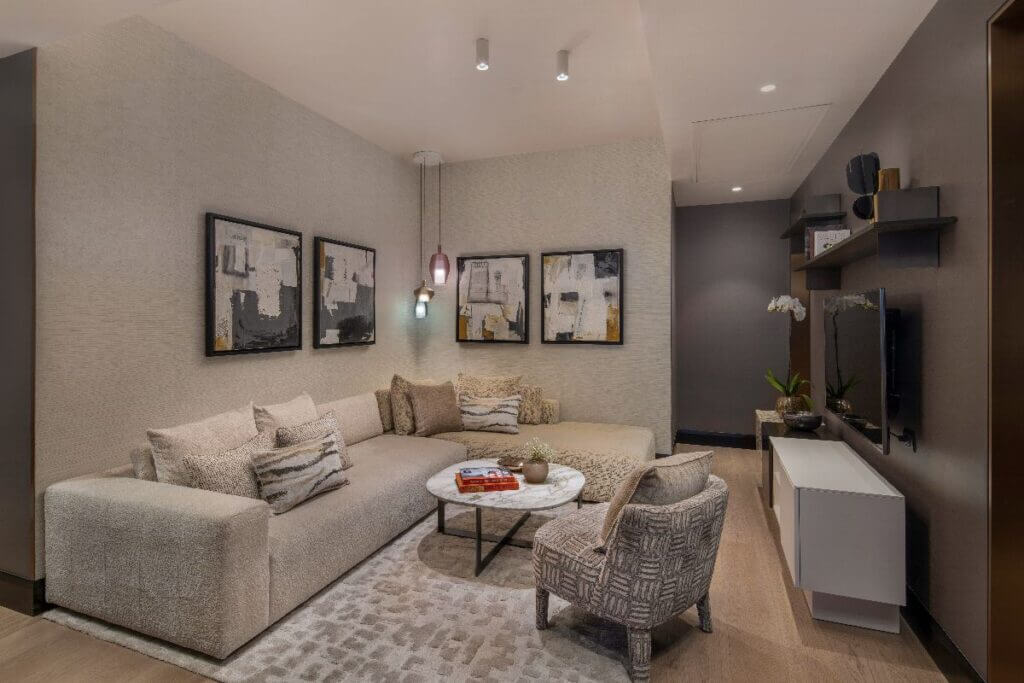 Contemporary living room featuring a large L-shaped sectional, patterned area rug, and modern wall art in neutral tones.