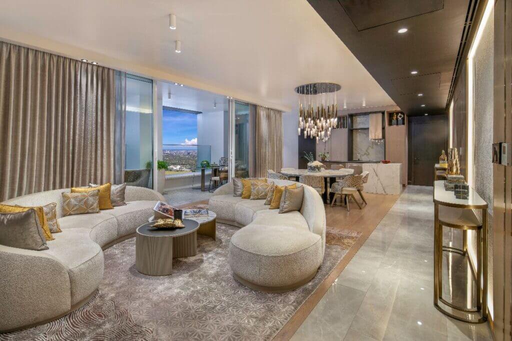 Modern open-plan living and dining area featuring a curved sectional sofa, marble coffee table, and urban views.