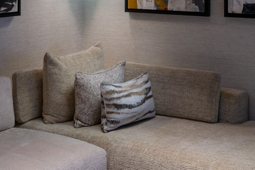 Close-up of neutral-toned sofa with textured decorative pillows in a contemporary interior setting.