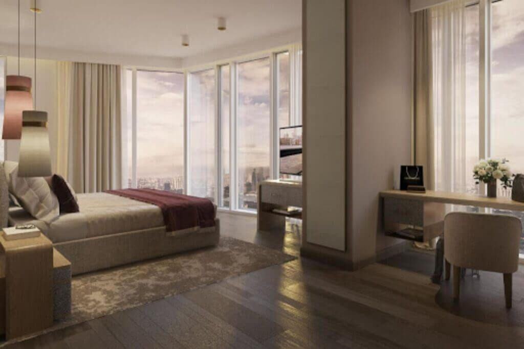 Master bedroom with floor-to-ceiling windows, dark wood flooring, and neutral-toned furniture in a luxury high-rise setting.