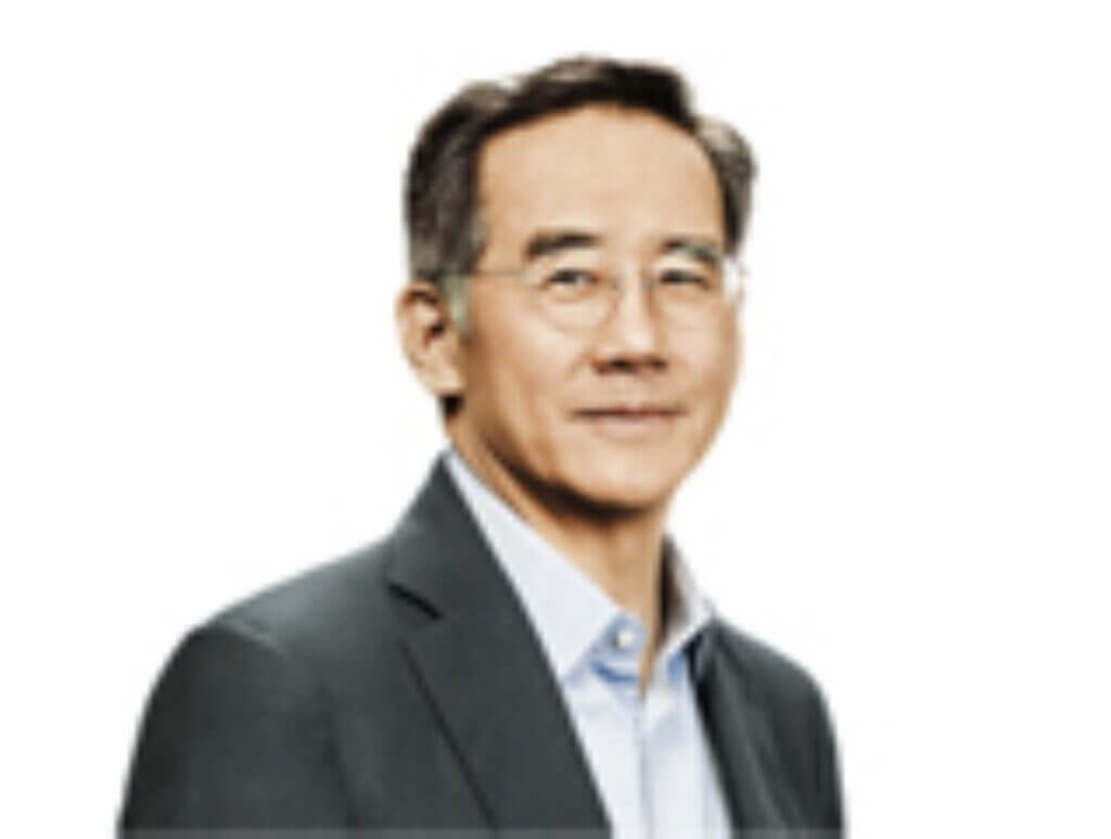 Headshot of an East Asian man with glasses, wearing a suit jacket and light blue shirt, smiling slightly against a white background.